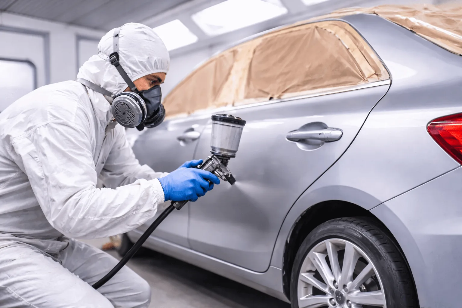 Profissional-realizando-pintura-automotiva-em-Bauru-com-cabine-de-pintura-e-pistola-de-alta-precisao