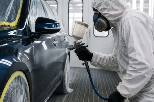 Close-de-profissional-utilizando-pistola-de-pintura-automotiva-em-carro-preto-dentro-de-cabine-profissional
